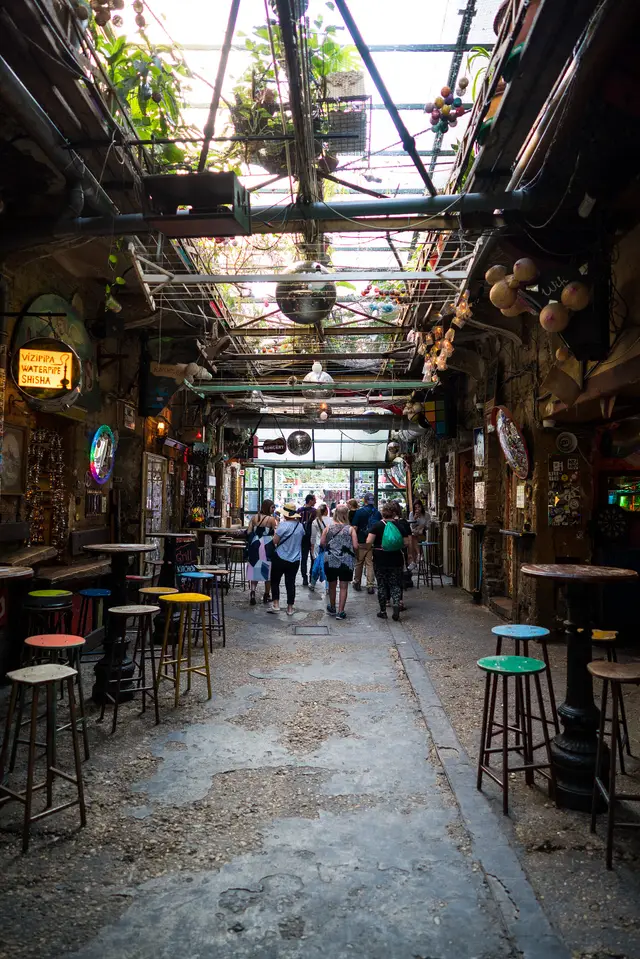 People at tables in the eclectic courtyard of the Szimpla Kert ruin bar