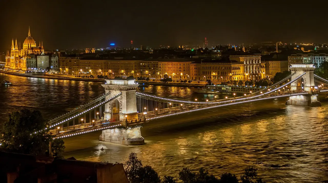 The Chain Bridge lit up at night over the Danube with Buda Castle glowing behind