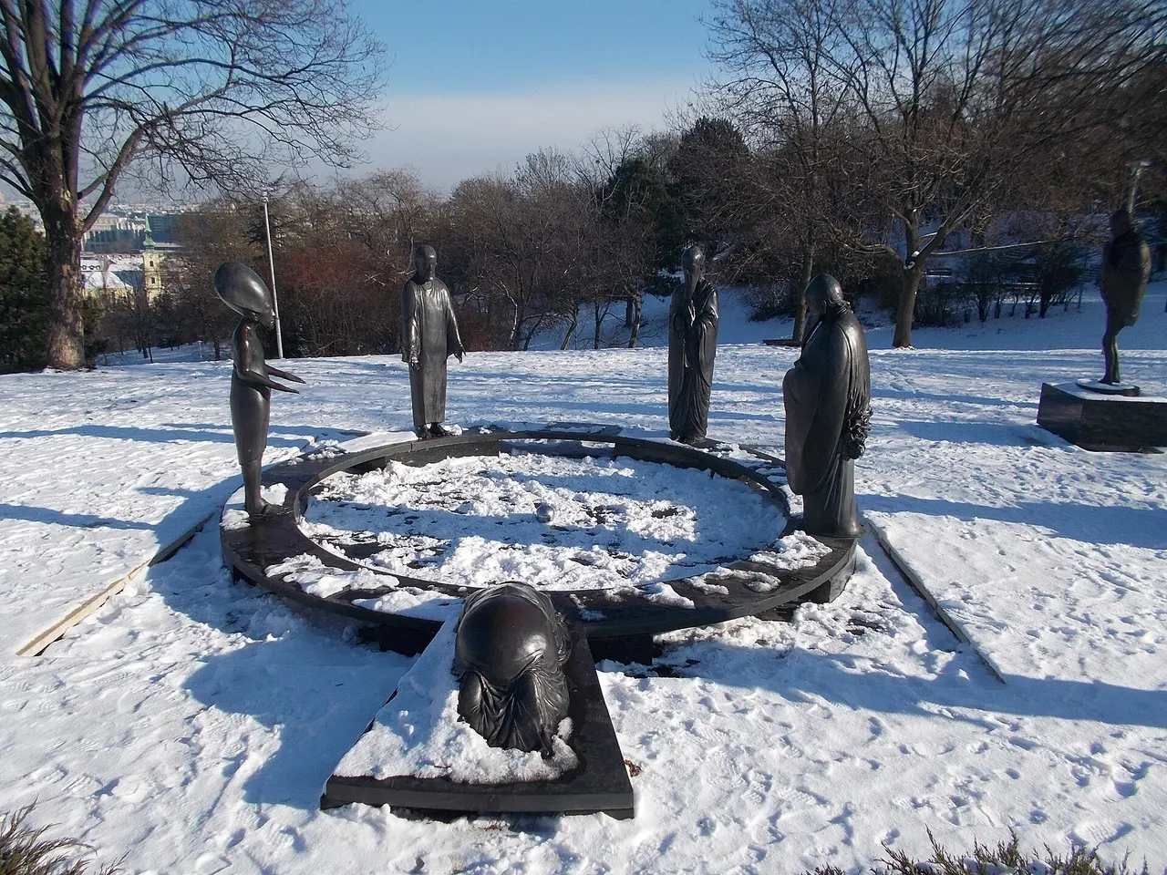 A ring of bronze philosopher statues in snow in the Garden of Philosophers on Gellért Hill