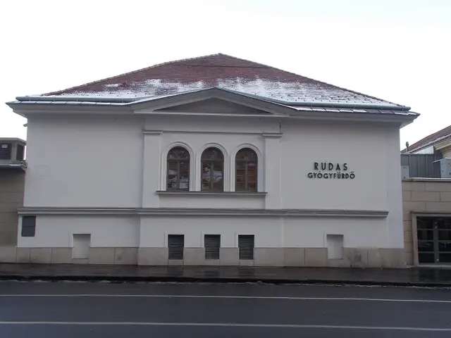 The plain white street facade of the Rudas Thermal Bath with its name above the windows