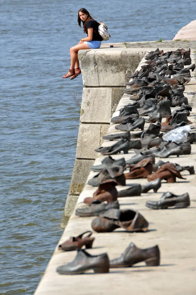 Rows of bronze shoes on the stone edge of the Danube embankment, the Shoes on the Danube Bank memorial